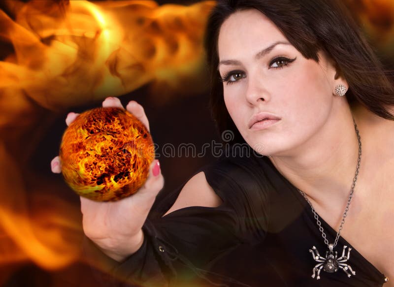 Bruja en alineada negra con la bola de fuego en la llama. imagen de archivo Bruja en alineada negra con la bola de fuego en la llama. imagen de archivo