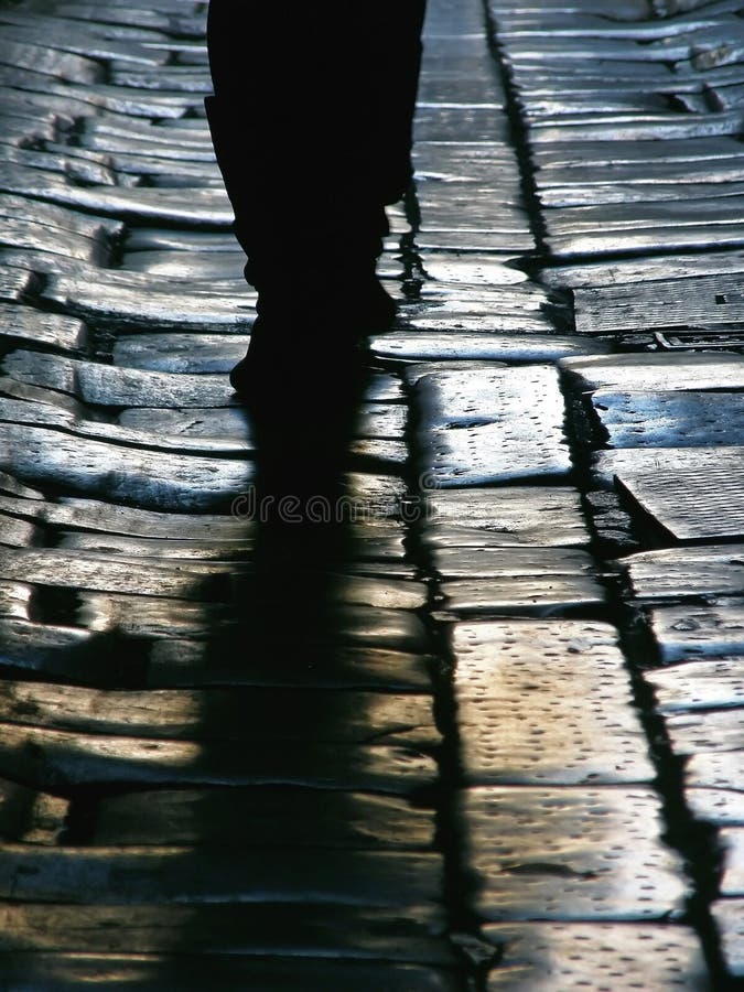 View of the old stone sidewalk and people - feet that walked on a cobbled street. Vertical color photo. View of the old stone sidewalk and people - feet that walked on a cobbled street. Vertical color photo.