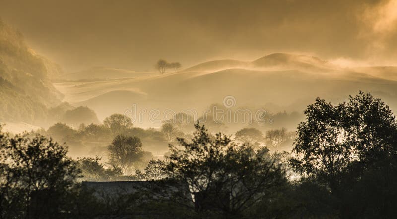 Beautiful ethereal countryside landscape coming to life as the sun burns of the early dawn morning mist. Beautiful ethereal countryside landscape coming to life as the sun burns of the early dawn morning mist.