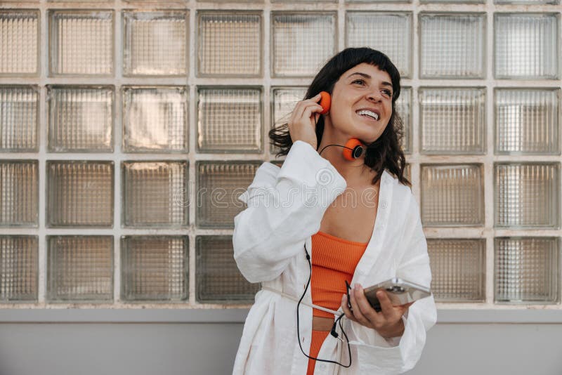 Brune joyeuse souriante femme tenant un casque et regardant loin image libre de droits