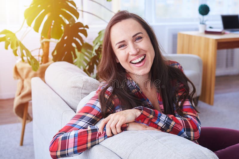 Brunet Laughing And Having Rest Sitting On Stylish Sofa