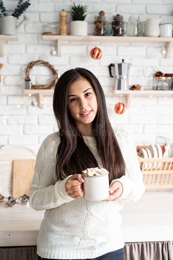 Brunetka trzymająca filiżankę piankowego kakao w kuchni fotografia stock