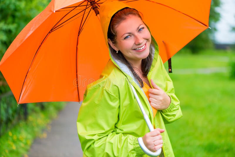 Brunetka śmia się pod pomarańczowym parasolem obrazy stock Brunetka śmia się pod pomarańczowym parasolem obrazy stock