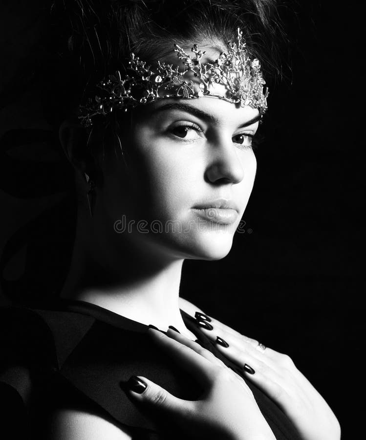 Brunetta attrattiva con una corona di tiara dorata sulla fronte, capelli travi, in un corpo nero intelligente, calzamaglia di nyl fotografia stock libera da diritti