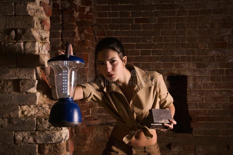 Brunette con un tesoro de la búsqueda de la linterna en las ruinas fotos de archivo libres de regalías Brunette con un tesoro de la búsqueda de la linterna en las ruinas fotos de archivo libres de regalías