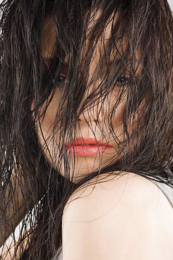 Close-up of nice brunette keeping wet hair in front of her face and looking sensual in camera. Close-up of nice brunette keeping wet hair in front of her face and looking sensual in camera