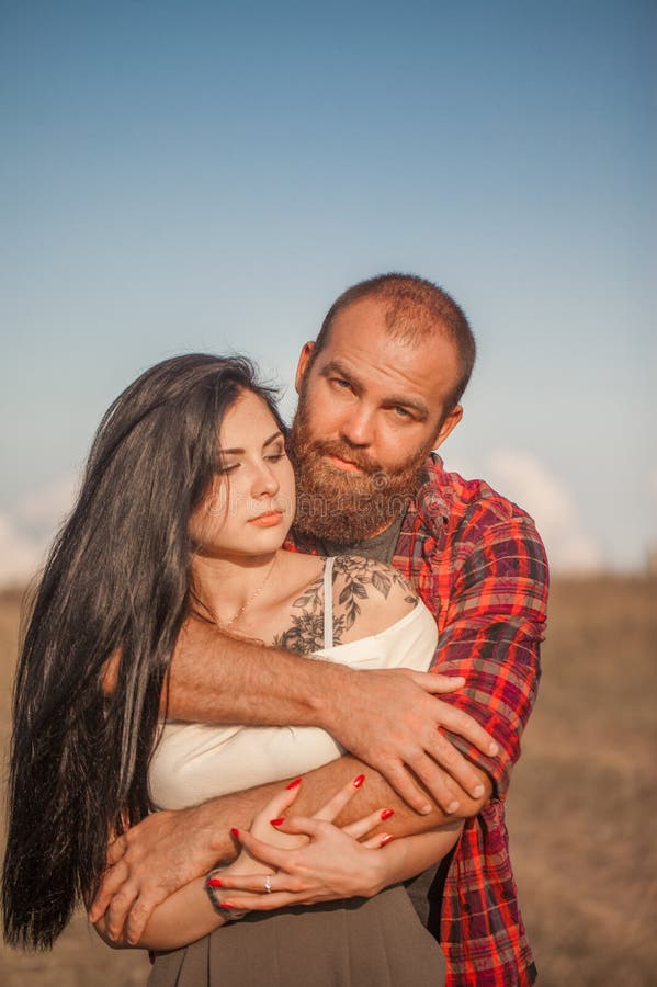 Brunette e brutale ragazzo con una storia d'amore alla barba. abbracci e fotografie stock