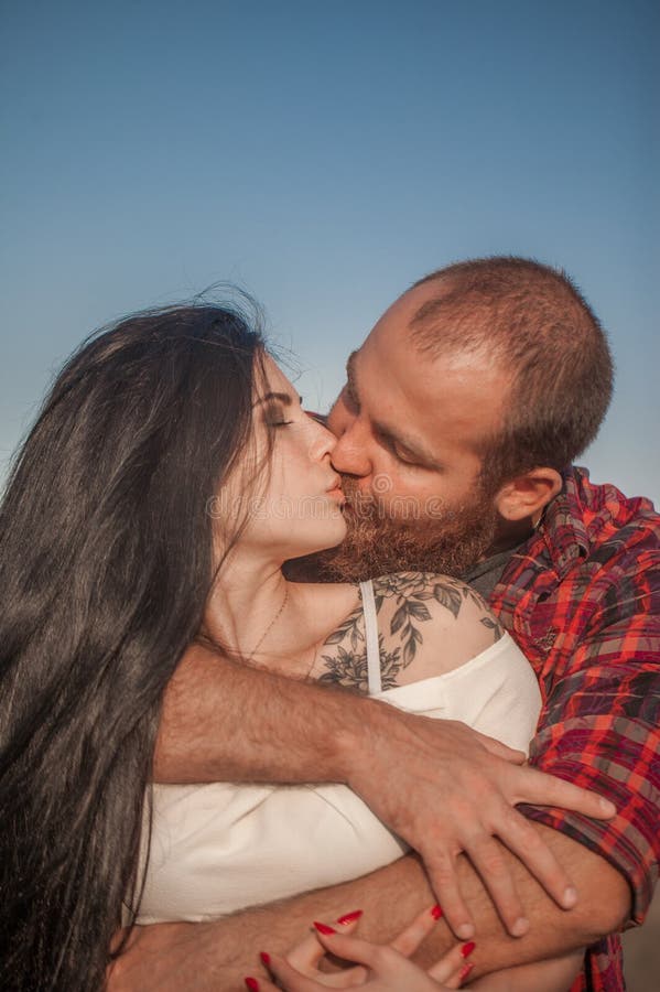 Brunette e brutale ragazzo con una storia d'amore alla barba. abbracci e fotografie stock
