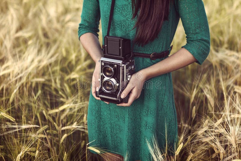 Brunette girl with retro camera in meadow