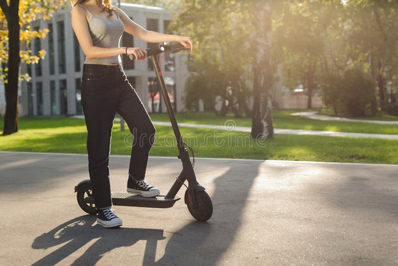 Brunette Girl Riding an Eco-friendly Electric Kick Scooter in a Park in ...