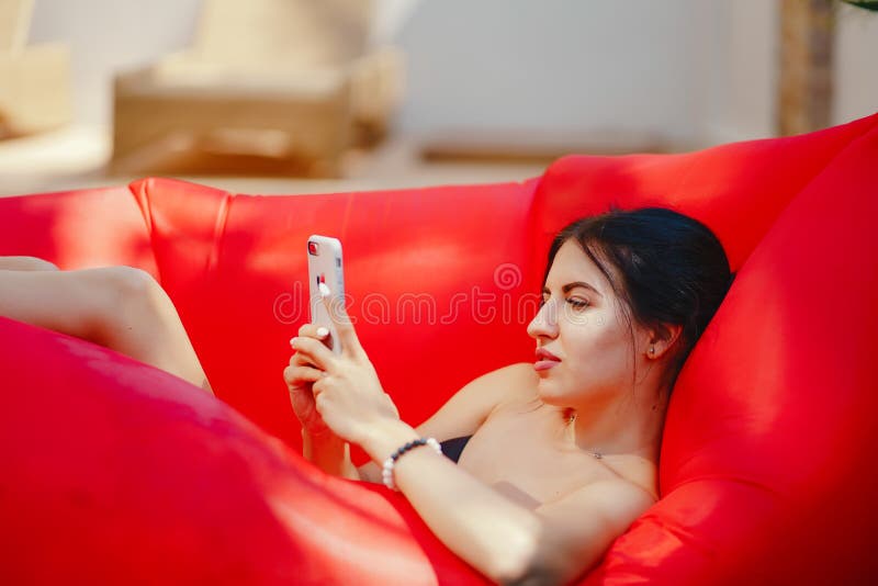 Brunette girl using and talking on her phone while floating in the pool. Brunette girl using and talking on her phone while floating in the pool