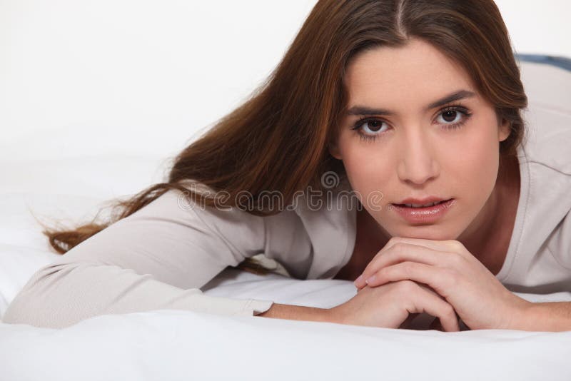 Brunette laying on bed royalty free stock photography