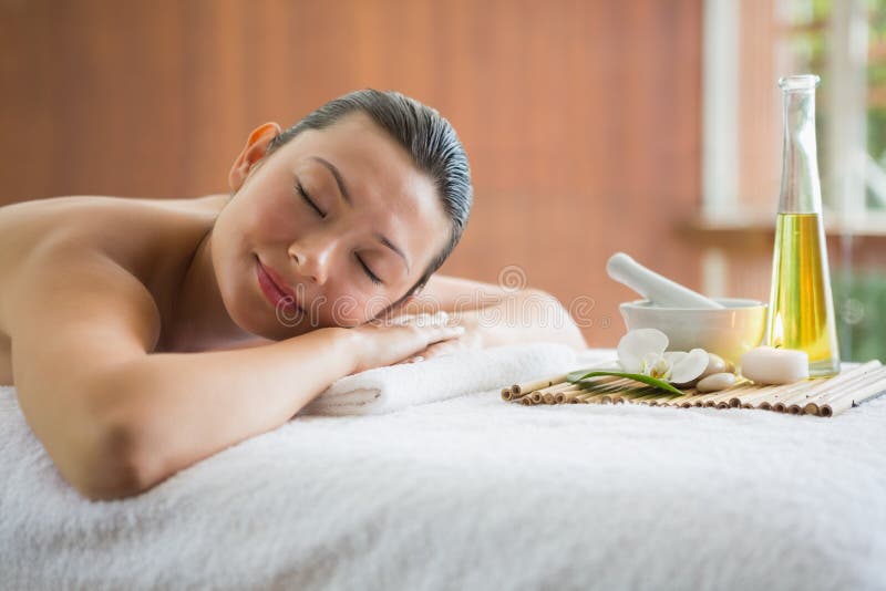 Brunette Lying On Massage Table With Tray Of Beauty Treatments Stock