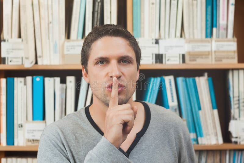 Brunette male librarian requesting silence in library