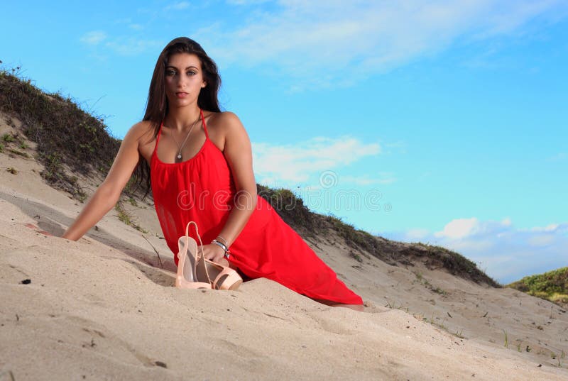 Brunette in red dress resting on the beach