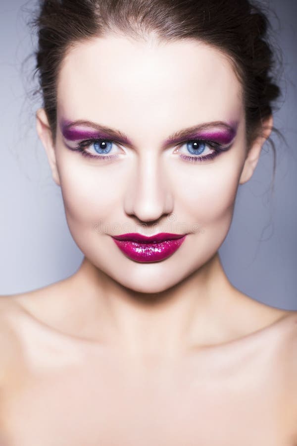 Brunette woman with creative make up violet eye shadows full red lips, blue eyes and curly hair with her hand on her face stock photos Brunette woman with creative make up violet eye shadows full red lips, blue eyes and curly hair with her hand on her face stock photos