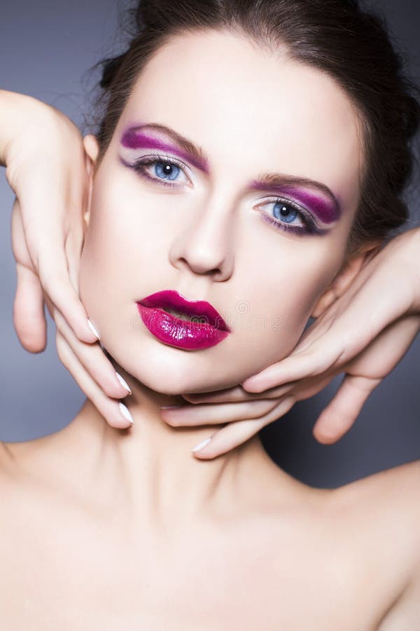 Brunette woman with creative make up violet eye shadows full red lips, blue eyes and curly hair with her hand on her face royalty free stock photo Brunette woman with creative make up violet eye shadows full red lips, blue eyes and curly hair with her hand on her face royalty free stock photo