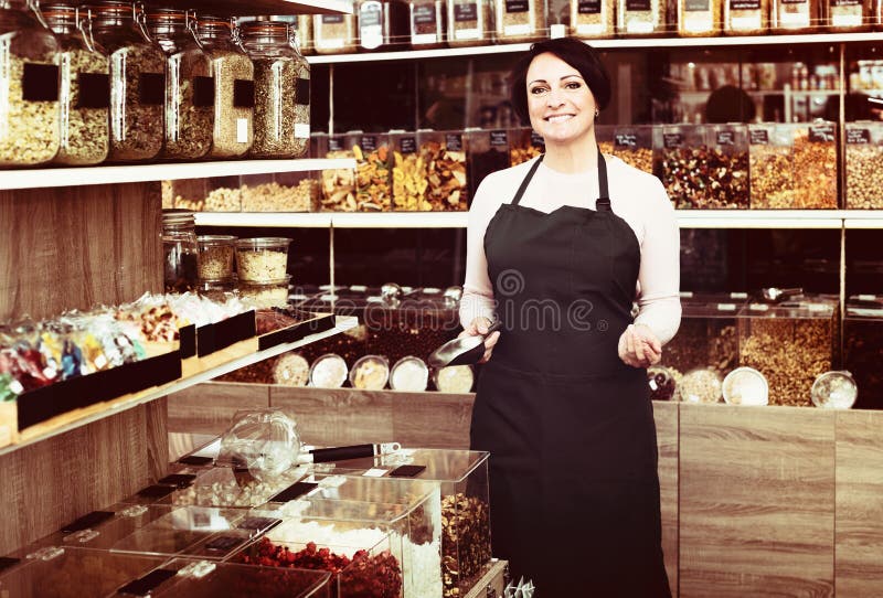 Brunette woman wearing apron and selling nuts stock photos Brunette woman wearing apron and selling nuts stock photos