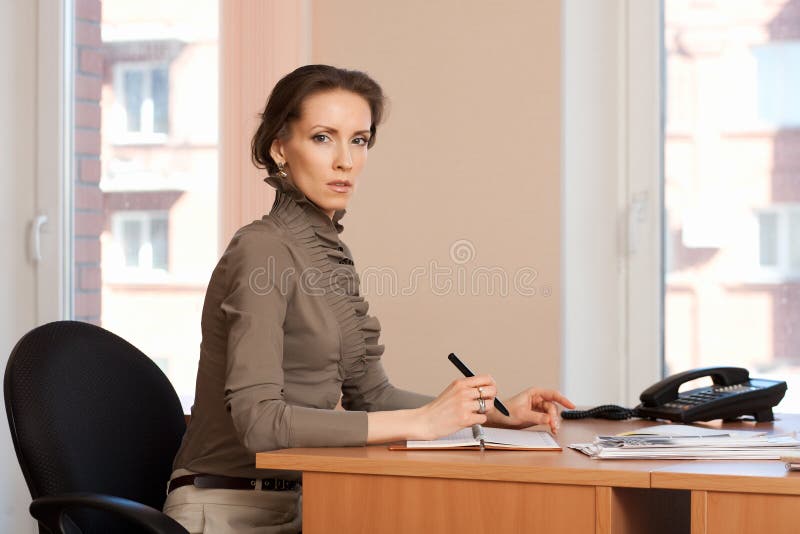 Brunette woman works in the office, makes notes