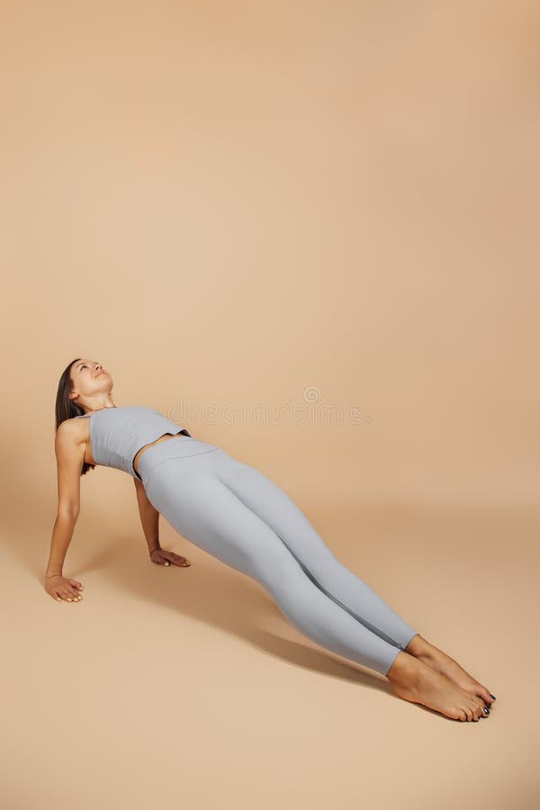 Brunette è impegnata in attività fisica. bella giovane donna con una tuta da yoga grigia che si adatta a una tuta da ginnastica fa fotografia stock libera da diritti