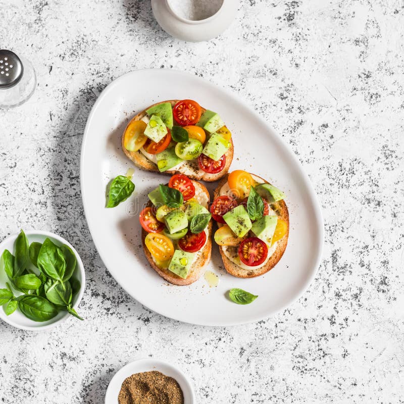 Bruschetta with cherry tomatoes, avocado and basil. On a light background. stock photos Bruschetta with cherry tomatoes, avocado and basil. On a light background. stock photos