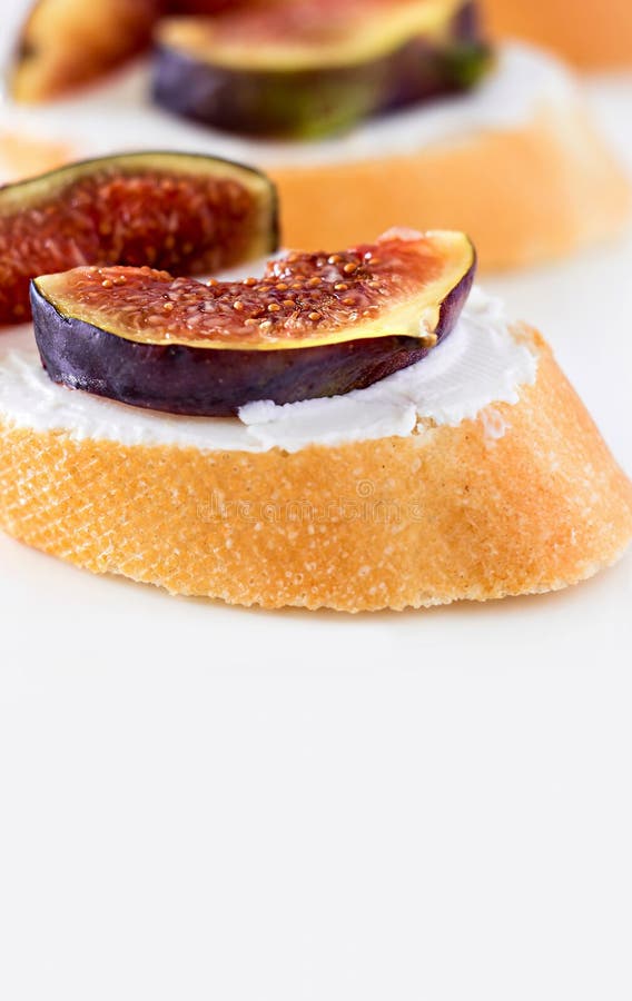 Bruschetta com figo e queijo de cabra no fundo branco raso imagem de stock Bruschetta com figo e queijo de cabra no fundo branco raso imagem de stock