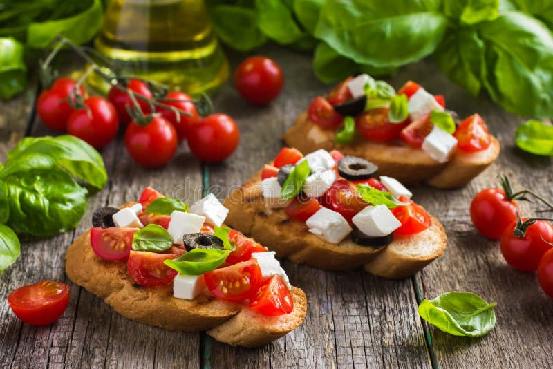 Bruschetta com tomate, queijo feta, azeitonas e manjericão imagem de stock
