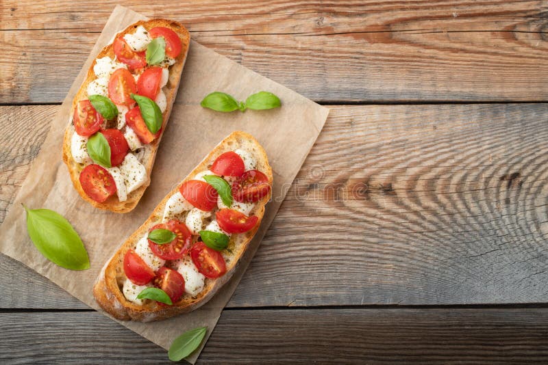 Bruschetta con los tomates, el queso de la mozzarella y la albahaca en una tabla rústica vieja Aperitivo o bocado italiano tradic foto de archivo libre de regalías Bruschetta con los tomates, el queso de la mozzarella y la albahaca en una tabla rústica vieja Aperitivo o bocado italiano tradic foto de archivo libre de regalías