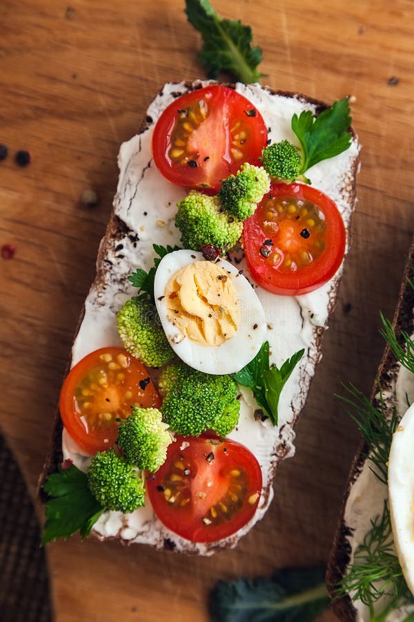 Bruschetta: om mörk brödostmassa, halvor av körsbärstomater, broccoli-, persilja- och kryddor royaltyfria bilder