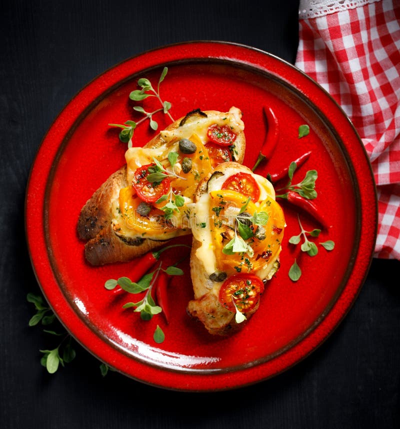 Bruschetta, piec na grillu baguette z dodatkiem pomidory, ser i ziele na czerwień talerzu