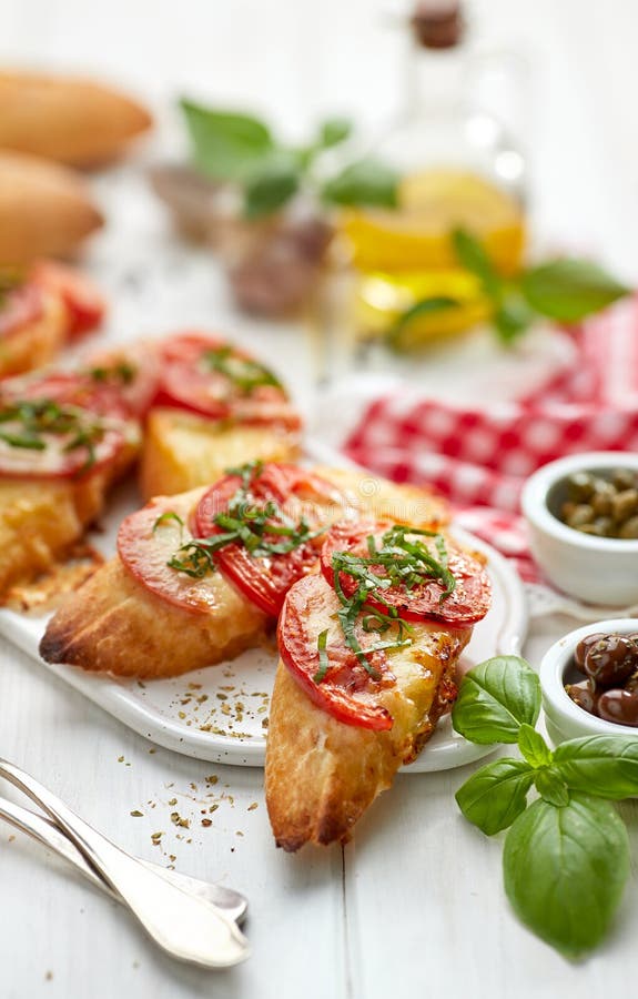 Bruschetta, piec na grillu plasterki baguette z mozzarella serem, pomidorami, czosnkiem i aromatycznym basilem na białym drewnian