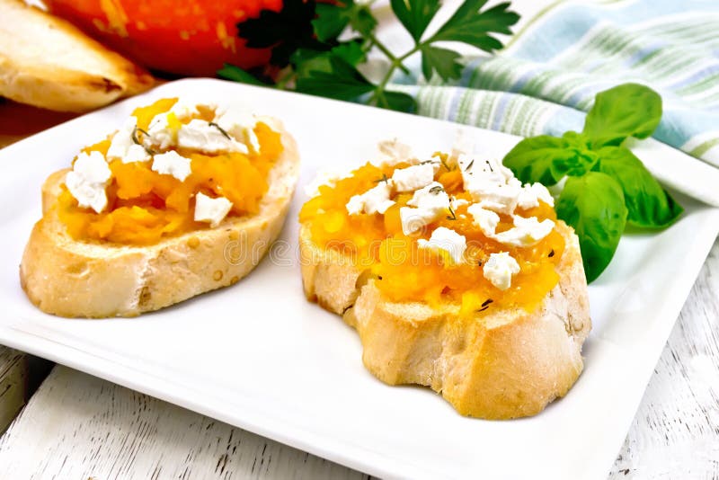 Bruschetta with pumpkin and feta in white plate on board stock photography Bruschetta with pumpkin and feta in white plate on board stock photography
