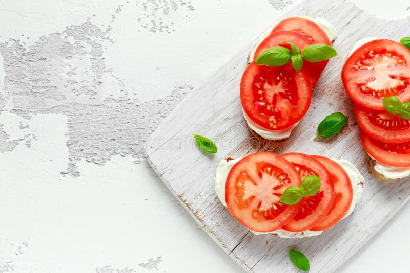 Bruschetta, toast with soft cheese, basil and tomatoes on a white wooden board. Italian healthy snack, food. royalty free stock image Bruschetta, toast with soft cheese, basil and tomatoes on a white wooden board. Italian healthy snack, food. royalty free stock image