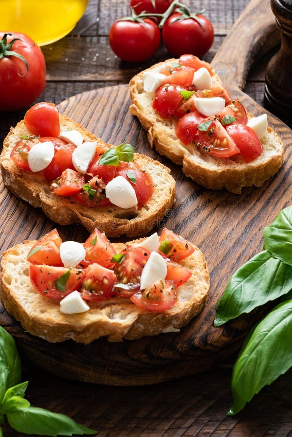 Bruschette de tomate et de mozzarella sur un conseil en bois photographie stock libre de droits Bruschette de tomate et de mozzarella sur un conseil en bois photographie stock libre de droits