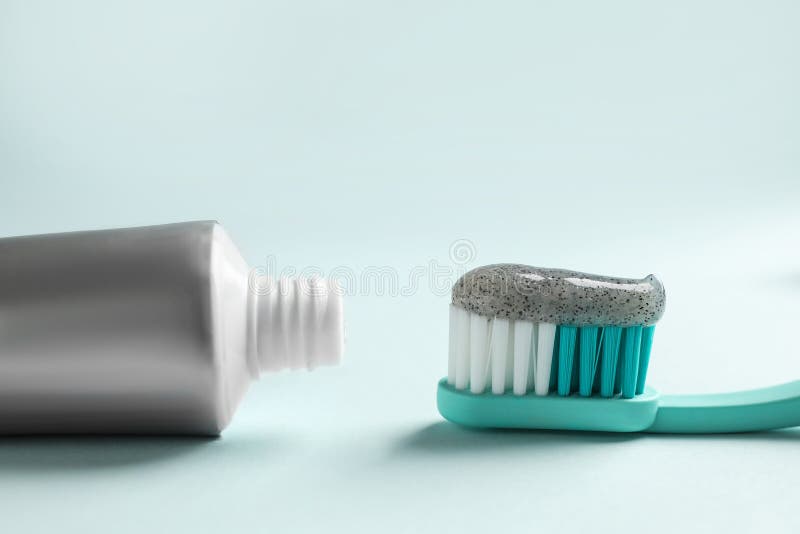 Brush with Charcoal Toothpaste and Tube on Light Background, Closeup
