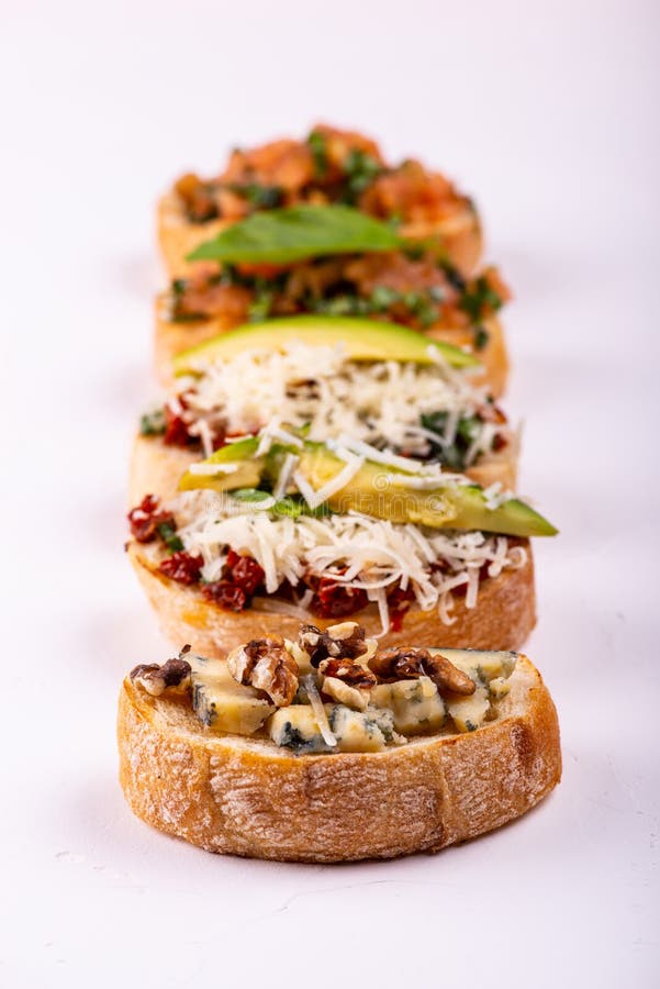 Brushetta ajustou-se para um aperitivo A variedade de sandu?ches pequenos com tomates, queijo parmes?o, abacate e noz serviu sobr fotos de stock Brushetta ajustou-se para um aperitivo A variedade de sandu?ches pequenos com tomates, queijo parmes?o, abacate e noz serviu sobr fotos de stock
