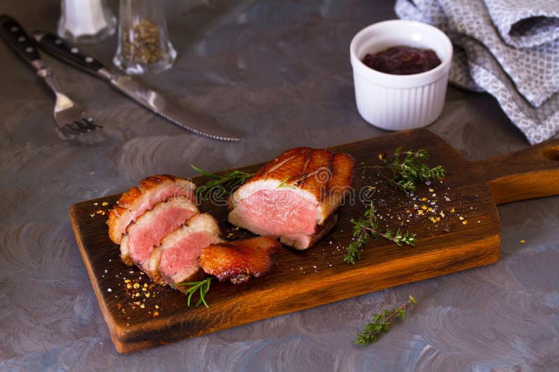 Brustfilets von Enten auf Holzplatte. Brust-Ente-Filets auf Holz serviert Brett und Cranberry-Sauce auf grauem Hintergrund