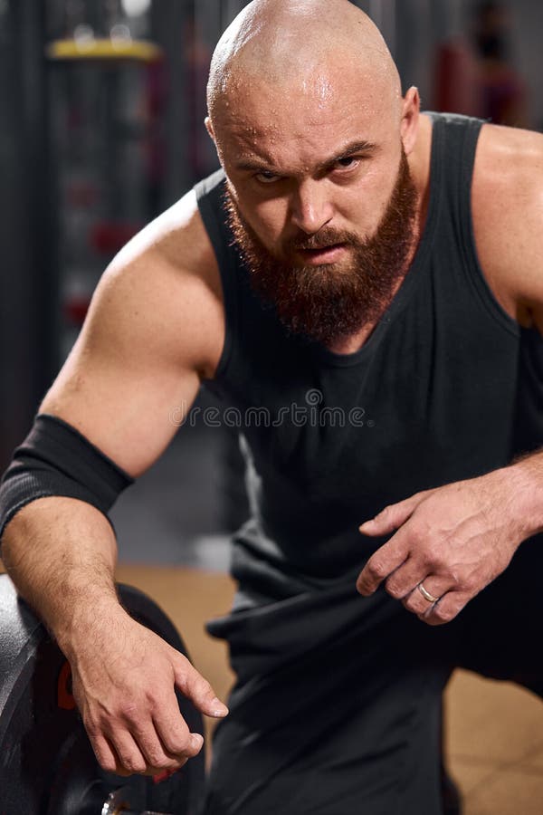 Foto de Brutal, muscular, bald with a beard athlete in the gym