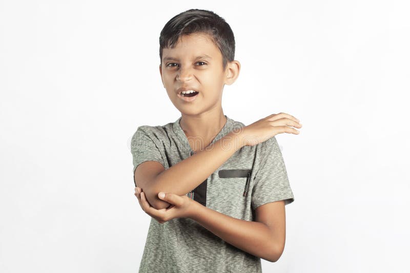 Bruten armsmärta som upplevs av en indian pojke som står mot vit bakgrund arkivbilder