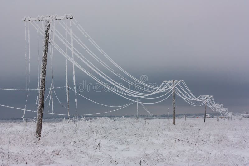 Brutna faselströmlinjer med rimfrost på de träelektriska polerna på bygd i vintern efter storm arkivfoto Brutna faselströmlinjer med rimfrost på de träelektriska polerna på bygd i vintern efter storm arkivfoto