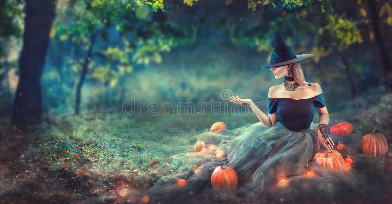 A bruxa de Dia das Bruxas com uma abóbora e uma mágica cinzeladas ilumina-se em uma floresta escura na noite Jovem mulher bonita