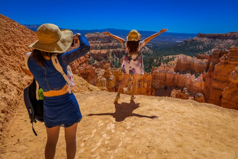 BRYCE CANYON, UTAH, JUNE, 07, 2018: Young Travelers taking pictures and standing on the cliff of Bryce Canyon National Park, Utah USA.