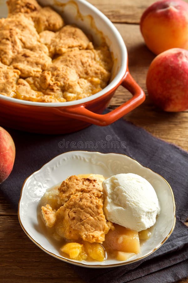 Homemade peach cobbler with vanilla ice cream over rustic wooden background - healthy pastry dessert. Homemade peach cobbler with vanilla ice cream over rustic wooden background - healthy pastry dessert