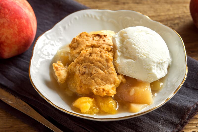 Homemade peach cobbler with vanilla ice cream over rustic wooden background - healthy pastry dessert. Homemade peach cobbler with vanilla ice cream over rustic wooden background - healthy pastry dessert