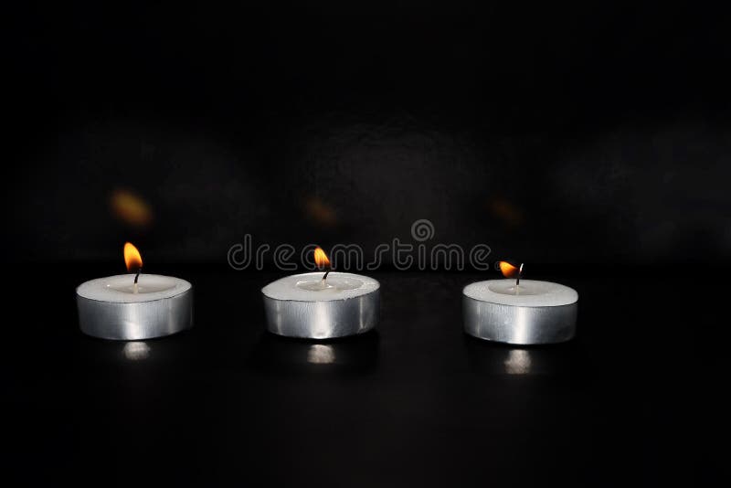 Burning candles on a black background. Photo for Israel Memorial Day, Holocaust Remembrance Day or Memorial Day for Fallen Soldiers and Victims of Hostile Acts. In Hebrew - Yom HaShoah, Yom HaZikaron. Burning candles on a black background. Photo for Israel Memorial Day, Holocaust Remembrance Day or Memorial Day for Fallen Soldiers and Victims of Hostile Acts. In Hebrew - Yom HaShoah, Yom HaZikaron