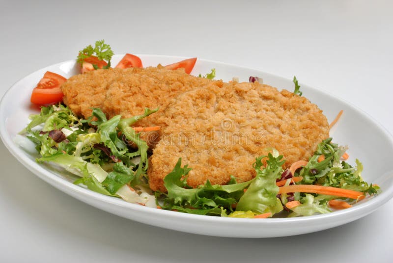 Panerad fiskbiff med örter på en tallrik royaltyfri fotografi