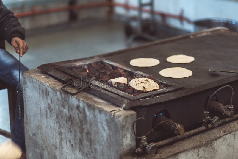 Bröd för lägenhet för manmatlagningindier som kallas chapati och grilla den på den levande flamman Tonad bild, tappningfilter arkivbild