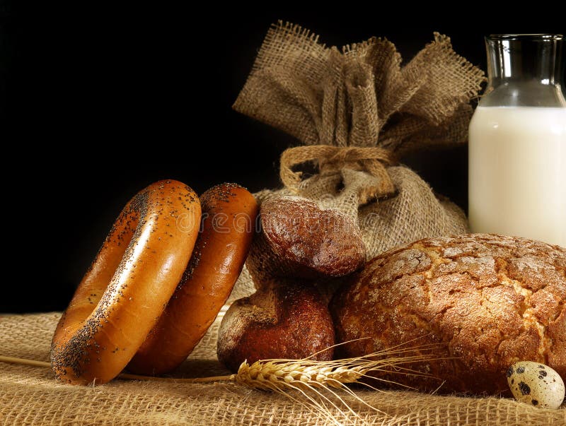 Bröd, spikelets och ägg i stilleben på en mörk bakgrund arkivbild