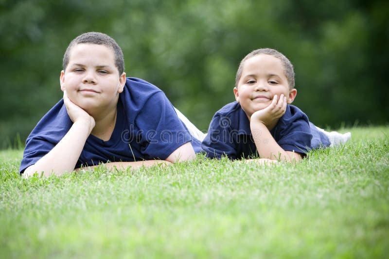 Two brothers lying on their fronts on fresh green grass. Two brothers lying on their fronts on fresh green grass