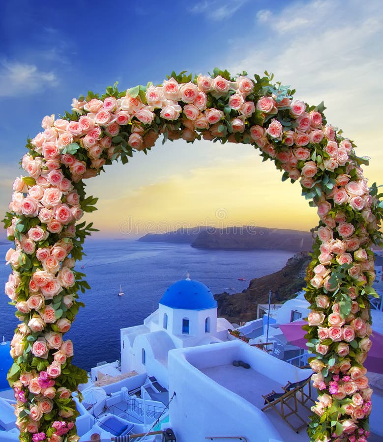 Bröllop på Santorini Härlig båge som vid de flesta dekoreras med blommor av rosor med den blåa kyrkan av Oia, Santorini, romantis arkivfoton Bröllop på Santorini Härlig båge som vid de flesta dekoreras med blommor av rosor med den blåa kyrkan av Oia, Santorini, romantis arkivfoton